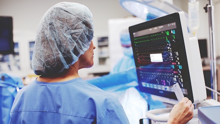Médica con la ropa para quirófano y gorro utilizando un monitor