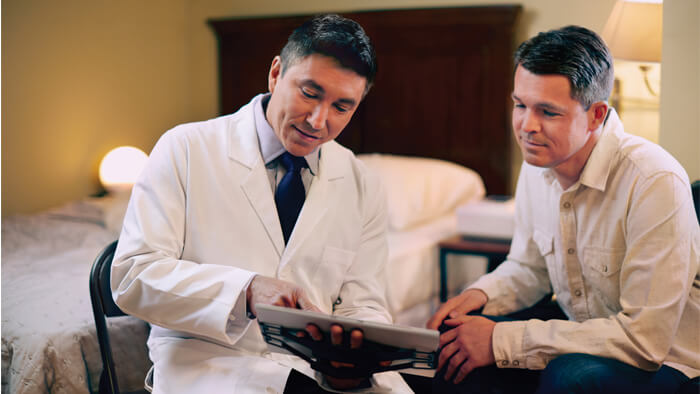 Fotografía de un médico mostrando a un hombre sus resultados en una tablet