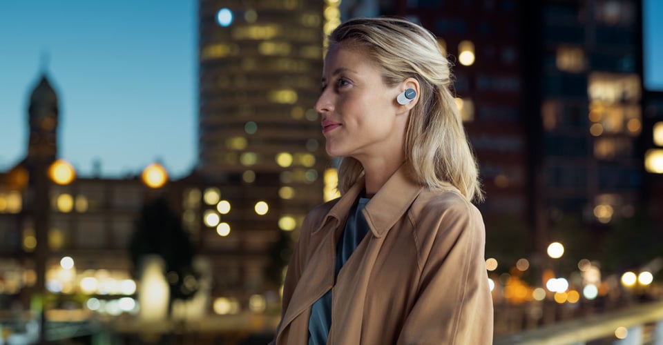 Mujer usando auriculares Philips con cancelación de ruido en la ciudad