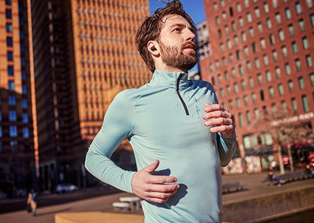 Hombre corriendo al aire libre escuchando música a través de auriculares inalámbricos verdaderos Philips A5508