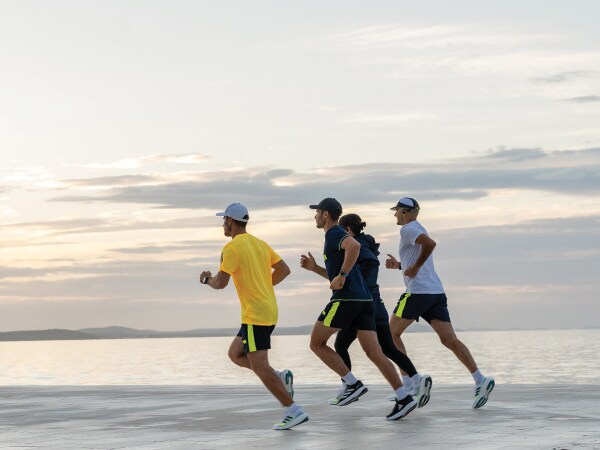 Cuatro participantes corren juntos en la playa.