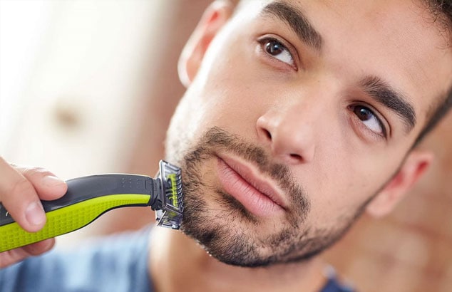 Un hombre afeitándose la barba corta desde la mejilla hasta la línea de la mandíbula, dejando una zona bien afeitada
