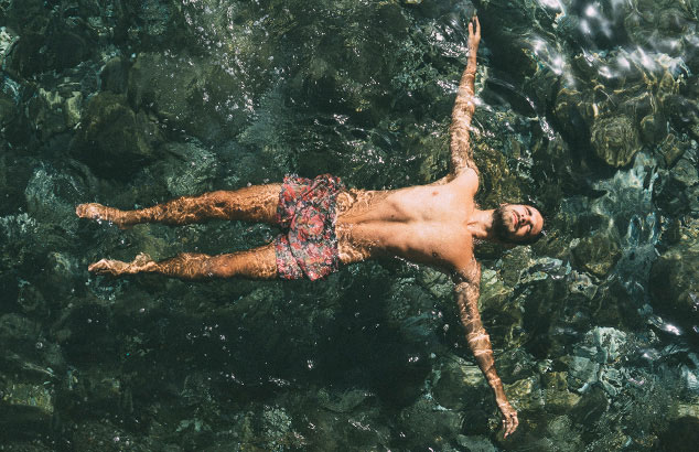 Un hombre bañándose en aguas abiertas con el cuerpo extendido