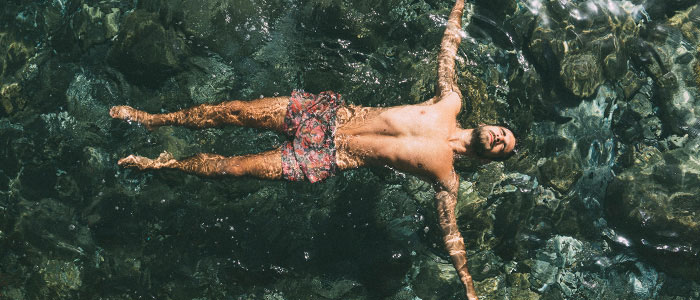 Un hombre bañándose en aguas abiertas con el cuerpo extendido
